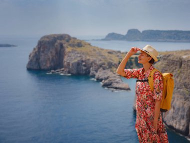 Yunan Adaları 'nda güneşli bir günün tadını çıkaran güzel mutlu kadın. Yunanistan 'a seyahat, turizm sezonu dışında Akdeniz adaları. Hayatın tadını çıkarmak ve denize bakmak. Turkuaz deniz arkaplanı.