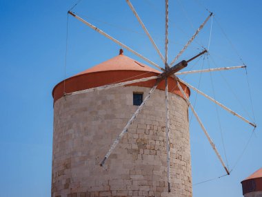 Yunanistan 'ın Rodos kentindeki Mandraki limanında yel değirmenleri. Eski savunma stantları ve yel değirmenleri. Rıhtım limanları, tekneler ve yelkenli gemiler. Tarihi iskele ve sahil. Akdeniz adalarına seyahat Rodos.