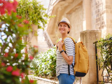 Yunanistan 'ın Rodos adasına yaz gezisi. Çizgili tişörtlü ve şapkalı genç Asyalı kadın Şövalyeler Kalesi 'nde yürüyor. Bayan gezgin Güney Avrupa 'yı ziyaret ediyor. Unesco Dünya Mirası Bölgesi