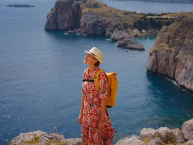 Yunan Adaları 'nda güneşli bir günün tadını çıkaran güzel mutlu kadın. Yunanistan 'a seyahat, turizm sezonu dışında Akdeniz adaları. Hayatın tadını çıkarmak ve denize bakmak. Turkuaz deniz arkaplanı.