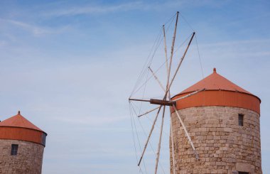 Yunanistan 'ın Rodos kentindeki Mandraki limanında yel değirmenleri. Eski savunma stantları ve yel değirmenleri. Rıhtım limanları, tekneler ve yelkenli gemiler. Tarihi iskele ve sahil. Akdeniz adalarına seyahat Rodos.
