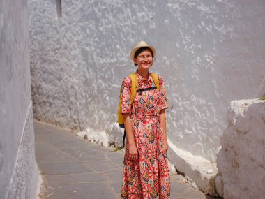 Yunan Adaları 'nda güneşli bir günün tadını çıkaran boho elbiseli güzel bir Asyalı kadın. Lindos 'a seyahat, Akdeniz adaları turizm sezonu. Yunanistan 'da tatilde olan turist kadın Lindos sokaklarında yürüyor.