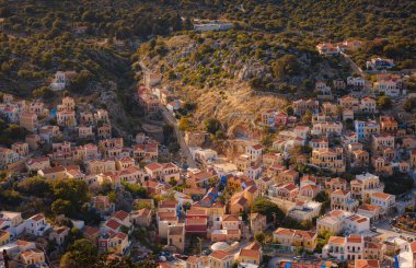 Symi Adası, Yunanistan. Yunanistan, Ege Denizi 'ndeki Rodos adalarından tatil yapıyor. Günbatımında bir Yunan adasının yamaçlarında renkli neoklasik güzel evler. Tatil seyahat arkaplanı.