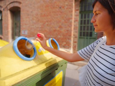 Avrupa caddesinde plastik şişe geri dönüşüm kutusu satan bir kadın. Dünyayı ve çevre bakımını kurtarmak için çöp kutusuna atılmadan önce atık ayıklama çöplüğü. Kirlilik çöpü geri dönüşüm yönetimi kavramı