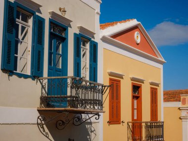 Pencereler, kapılar, Simi Adası 'ndaki eski evlerin balkonları. Yunanistan, Ege Denizi 'ndeki Rodos adalarından tatil yapıyor. Symi Körfezi 'ndeki renkli neoklasik evler. Tatil seyahat arkaplanı.