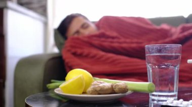 Zencefil, limon, soğan ve arka plandaki hasta adamın üzerinde farklı uyuşturucular. Alternatif ilaçlar ve soğuk algınlığı ve grip tedavisi için geleneksel haplar. Arka planda kırmızı battaniyeye sarılı hasta adam.