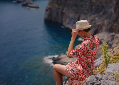 Yunan Adaları 'nda güneşli bir günün tadını çıkaran güzel mutlu kadın. Yunanistan 'a seyahat, turizm sezonu dışında Akdeniz adaları. Hayatın tadını çıkarmak ve denize bakmak. Turkuaz deniz arkaplanı.