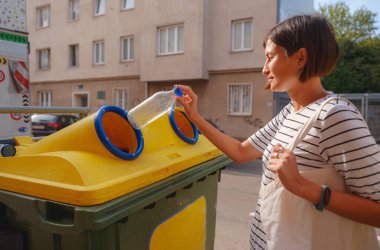 Avrupa caddesinde plastik şişe geri dönüşüm kutusu satan bir kadın. Dünyayı ve çevre bakımını kurtarmak için çöp kutusuna atılmadan önce atık ayıklama çöplüğü. Kirlilik çöpü geri dönüşüm yönetimi kavramı