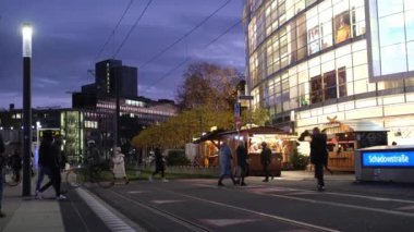 Düsseldorf, Almanya - 13 Aralık 2022: Şehir merkezinde akşam koşuşturması, toplu taşıma, tramvay raylarından geçen insanlar. Noel atmosferi kışın Düsseldorf caddesinde.