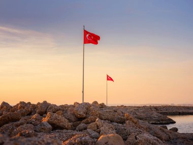 Türkiye 'nin Antalya kıyısındaki Antik Kenti' ne düşük turizm sezonunda gitmek. Türk bayrakları, günbatımı gökyüzünün arka planına karşı