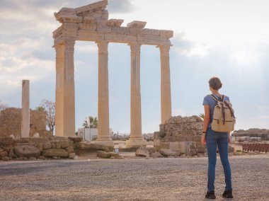 Türkiye 'nin Antalya kıyısındaki Antik Kenti' ne düşük turizm sezonunda gitmek. Genç turist Asyalı kadın Apollo tapınağının önünde poz veriyor.