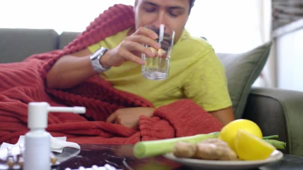 秋と冬の季節のくしゃみ 白人男性は 自宅のリビングルームで水で薬やビタミンを受け取ります 治療コンセプト — ストック動画
