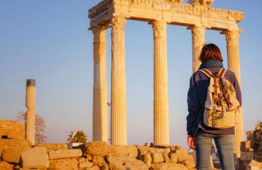 Türkiye 'nin Antalya kıyısındaki Antik Kenti' ne düşük turizm sezonunda gitmek. Genç turist Asyalı kadın Apollo tapınağının önünde poz veriyor.