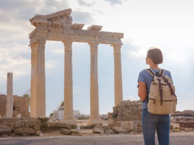 Türkiye 'nin Antalya kıyısındaki Antik Kenti' ne düşük turizm sezonunda gitmek. Genç turist Asyalı kadın Apollo tapınağının önünde poz veriyor.