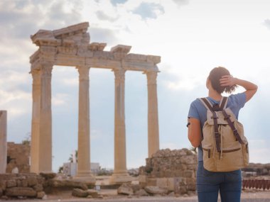 Türkiye 'nin Antalya kıyısındaki Antik Kenti' ne düşük turizm sezonunda gitmek. Genç turist Asyalı kadın Apollo tapınağının önünde poz veriyor.