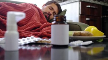 Zencefil, limon, soğan ve arka plandaki hasta adamın üzerinde farklı uyuşturucular. Alternatif ilaçlar ve soğuk algınlığı ve grip tedavisi için geleneksel haplar. Arka planda kırmızı battaniyeye sarılı hasta adam.