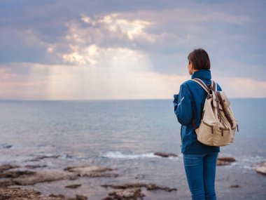 Türkiye 'nin Antalya kıyısındaki Antik Kenti' ne düşük turizm sezonunda gitmek. Kadın turist denizin üzerinde güneşe bakıyor.