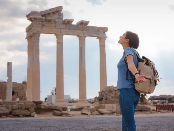 travel to ancient city of Side, Antalya coast of Turkey in tourist low season. Young tourist Asian woman is posing in front of temple of Apollo