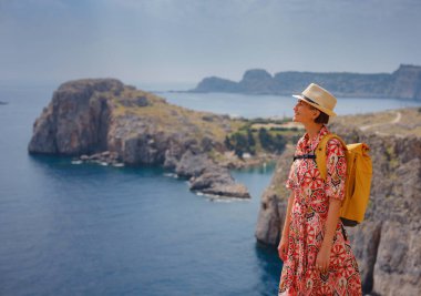 Yunan Adaları 'nda güneşli bir günün tadını çıkaran güzel mutlu kadın. Yunanistan 'a seyahat, turizm sezonu dışında Akdeniz adaları. Hayatın tadını çıkarmak ve denize bakmak. Turkuaz deniz arkaplanı.