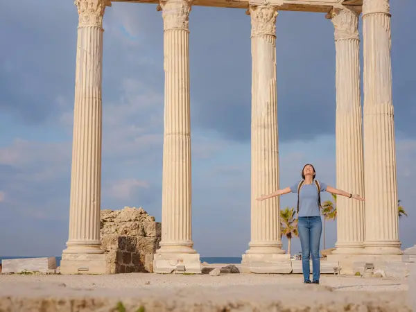 Türkiye 'nin Antalya kıyısındaki Antik Kenti' ne düşük turizm sezonunda gitmek. Genç turist Asyalı kadın Apollo tapınağının önünde poz veriyor.