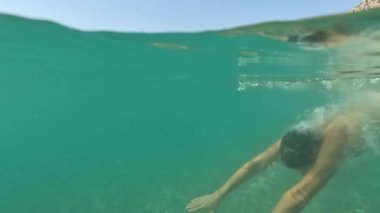Deniz yazı manzarası. Seyahat ve tatil konsepti. Suyun altında yüzen genç adamın yan görüntüsü. Antalya Türkiye deniz kıyısı, Akdeniz