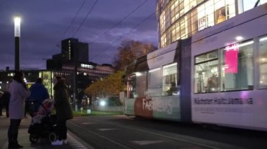 Düsseldorf, Almanya - 13 Aralık 2022: Şehir merkezinde akşam koşuşturması, toplu taşıma, tramvay raylarından geçen insanlar. Noel atmosferi kışın Düsseldorf caddesinde.