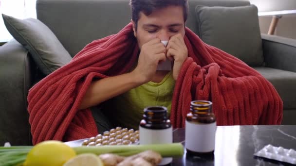 鼻抜けの若い白人男性は 自宅に座っている顔の近くに紙のナプキンを保持しています 病気の男は コビドの症状を示す悪い風邪を捕まえました またはウイルス病に苦しんでいます — ストック動画