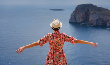 Yunan Adaları 'nda güneşli bir günün tadını çıkaran güzel mutlu kadın. Yunanistan 'a seyahat, turizm sezonu dışında Akdeniz adaları. Hayatın tadını çıkarmak ve denize bakmak. Turkuaz deniz arkaplanı.