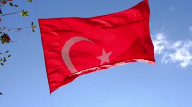 Türkiye 'nin büyük parlak bayrağı, mavi gökyüzü ve çok güçlü rüzgarlı bulutlara karşı yerden yükseklerde bayrak direğinde dalgalanıyor.