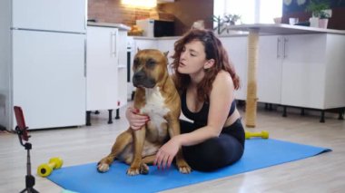 Evde yoga egzersizi yapan bir kadın ve yerde yatan bir köpek. Spor Giysileri Giyen Güzel Kadın Mat 'te Farklı Asana Pozisyonları Çalışıyor. Sağlıklı kadın yaşam tarzı ve evcil hayvan