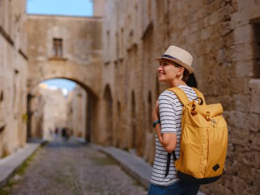 Yunanistan 'ın Rodos adasına yaz gezisi. Çizgili tişörtlü ve şapkalı genç Asyalı kadın Şövalyeler Kalesi 'nde yürüyor. Bayan gezgin Güney Avrupa 'yı ziyaret ediyor. Unesco Dünya Mirası Bölgesi