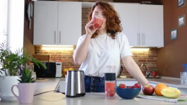 Ev mutfağındaki blender 'da meyveli smoothie deneyen bir kadın. Sağlıklı yeme, vejetaryenlik ve bilinçli yeme kavramı