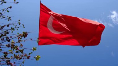 Türkiye 'nin büyük parlak bayrağı, mavi gökyüzü ve çok güçlü rüzgarlı bulutlara karşı yerden yükseklerde bayrak direğinde dalgalanıyor.
