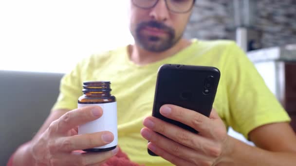 男人用智能手机学习吃药的方法 病人坐在客厅的沙发上 家庭医药概念 流感缓解片 医疗建议 — 图库视频影像