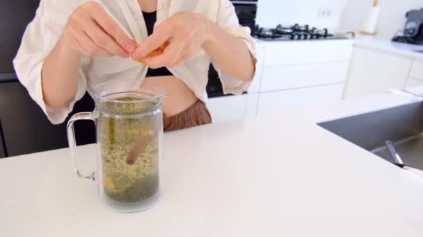 女人在厨房里做草药茶 她在茶壶里加了薄荷叶 柠檬香脂 百里香和迷迭香 女人喜欢香甜可口的饮料 — 图库视频影像