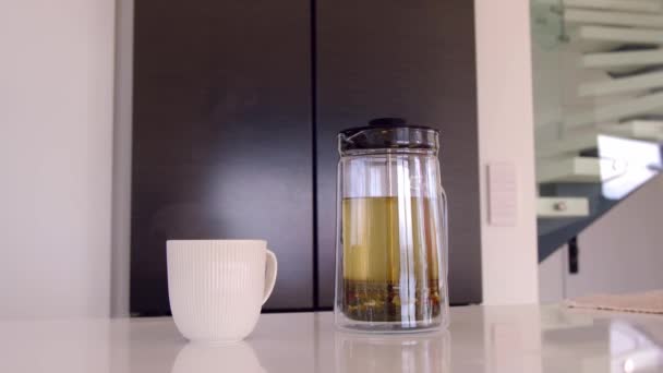 キッチンテーブルにハーブティースタンドのガラスティーポット 紅茶は その香りがキッチンを満たしています おいしいアロマティックな飲み物をお楽しみください — ストック動画