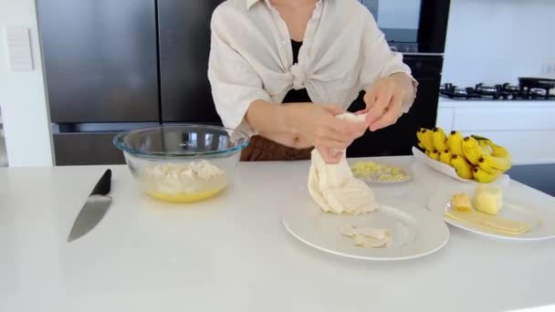 キッチンにいる女性は宿題をする 女性はテーブルでボウルにチーズでオムレツをかき混ぜる 家庭用キッチンインテリア 朝食の準備 — ストック動画
