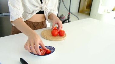 Beyaz modern mutfaktaki masada domates kesen kadın elleri. Sağlıklı yemek ve diyet konsepti. Zayıflama Ağırlığı