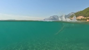 Deniz yazı manzarası. Seyahat ve tatil konsepti. Bikini giymiş kadınların tamamı, mavi denizde güneş ışınlarıyla suya dalıyor, Antalya 'da yaz tatili, Türkiye' de deniz kıyısında.