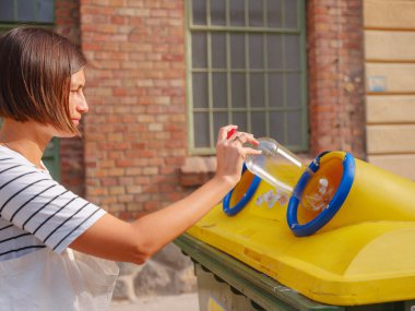 Avrupa caddesinde plastik şişe geri dönüşüm kutusu satan bir kadın. Dünyayı ve çevre bakımını kurtarmak için çöp kutusuna atılmadan önce atık ayıklama çöplüğü. Kirlilik çöpü geri dönüşüm yönetimi kavramı
