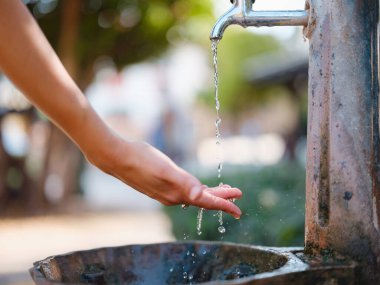 Antalyas eski kasaba: Kadın eli zarif bir şekilde çeşmeye uzanır, tarihi cazibenin ortasında ferahlatıcı bir vaha, tarihten ve sükunetten bir yudum sunar