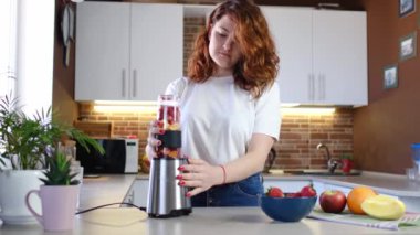 Mutfaktaki genç bayan meyve püresi yapıyor. Güzel, mutlu, genç bir bayan, günlük mutfağında evde fitness kokteyli hazırlıyor. Sportif ve vejetaryen yemeği.