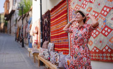 Antalya, Türkiye 'ye yaz seyahati. Kırmızı elbiseli genç Asyalı kadın eski şehir Kalechi 'den geçiyor. Kadın turist ilginç yerler ve geleneksel turist halısı keşfediyor.