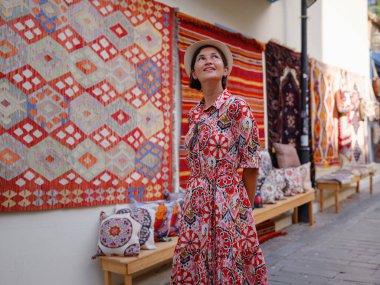 Antalya, Türkiye 'ye yaz seyahati. Kırmızı elbiseli genç Asyalı kadın eski şehir Kalechi 'den geçiyor. Kadın turist ilginç yerler ve geleneksel turist halısı keşfediyor.