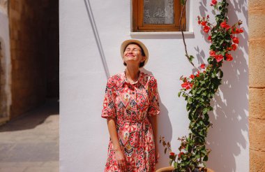 Yunan Adaları 'nda güneşli bir günün tadını çıkaran boho elbiseli güzel bir Asyalı kadın. Lindos 'a seyahat, Akdeniz adaları turizm sezonu. Yunanistan 'da tatilde olan turist kadın Lindos sokaklarında yürüyor.