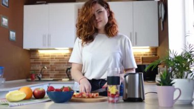 Mutfaktaki genç bayan meyve püresi yapıyor. Güzel, mutlu, genç bir bayan, günlük mutfağında evde fitness kokteyli hazırlıyor. Sportif ve vejetaryen yemeği.