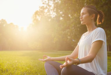 Genç Asyalı bir kadın sabah veya akşam parkta meditasyon yapıyor sağlıklı bir kadın şehir parkında yoga yapıyor. Farkındalık, kararlılık, sağlıklı alışkanlıklar ve denge konsepti