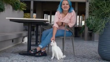 Kadın sokakta beyaz kedi besliyor. Kadınlar gülümser, hayvanlarla etkileşimden zevk alırlar. Hayvanlara iyi davranılması ve yardım edilmesi. Türk Kafesi ve Sokak Kedileri