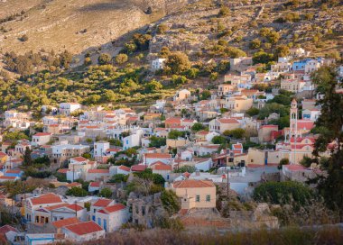 Symi Adası, Yunanistan. Yunanistan, Ege Denizi 'ndeki Rodos adalarından tatil yapıyor. Günbatımında bir Yunan adasının yamaçlarında renkli neoklasik güzel evler. Tatil seyahat arkaplanı.