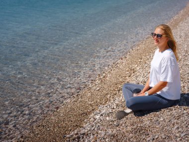 Antalya 'da Konyaalti seti boyunca yürümek, sahilde denize yakın bir yerde kahve içmek. Okyanus kıyısında kahkahalarla gülen neşeli sarışın kadın.